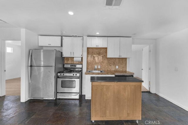 kitchen featuring visible vents, backsplash, a center island, appliances with stainless steel finishes, and white cabinetry