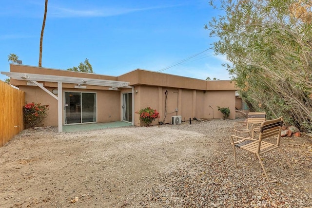 rear view of house with stucco siding, a patio, and fence