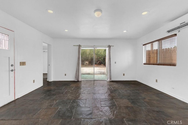 empty room featuring stone tile floors, recessed lighting, baseboards, and a wall mounted AC