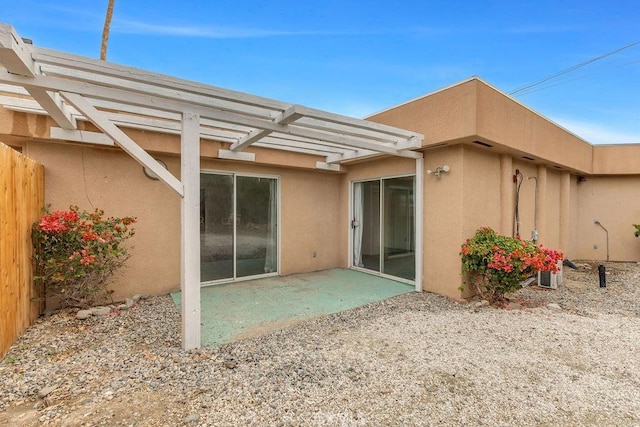 rear view of house with stucco siding, a patio, fence, and a pergola