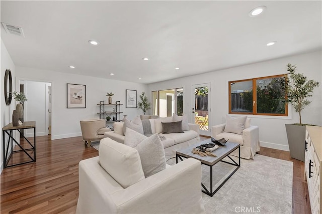 living room with recessed lighting, wood finished floors, visible vents, and baseboards