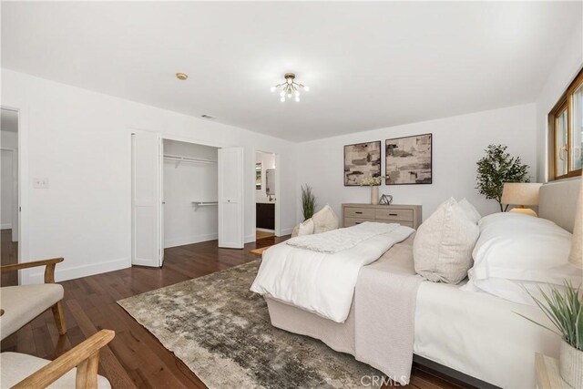 bedroom featuring dark wood finished floors, connected bathroom, baseboards, and a closet