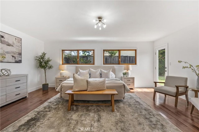 bedroom featuring baseboards, multiple windows, and wood finished floors