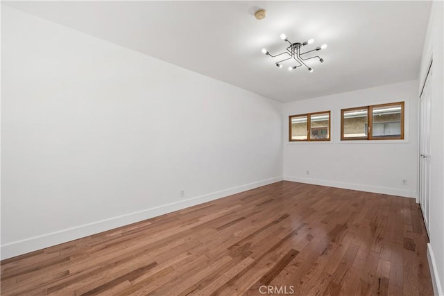 spare room featuring baseboards and wood finished floors