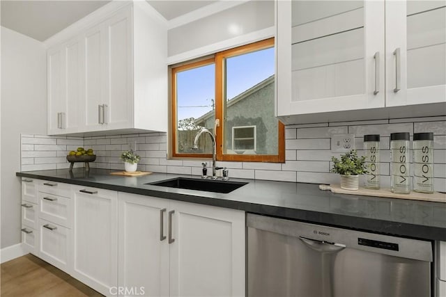 kitchen with white cabinetry, a sink, decorative backsplash, dishwasher, and dark countertops