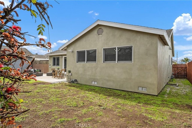 rear view of property featuring stucco siding, a fenced backyard, a yard, crawl space, and a patio area