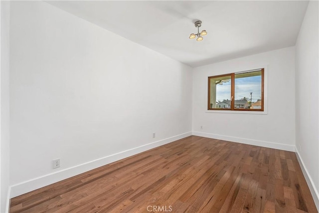 empty room with baseboards and hardwood / wood-style floors