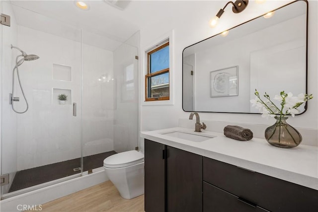 bathroom with vanity, a shower stall, toilet, and wood finished floors