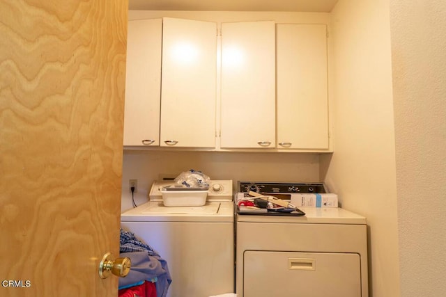 clothes washing area featuring cabinet space and washer and clothes dryer