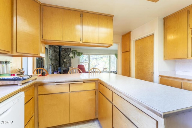 kitchen with light countertops, a wood stove, a peninsula, and white dishwasher