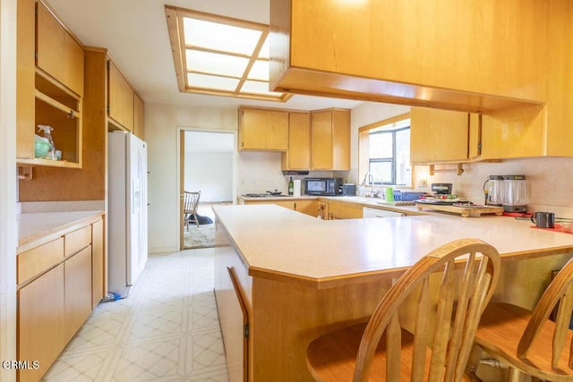 kitchen featuring light floors, a peninsula, white refrigerator with ice dispenser, and light countertops