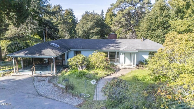 ranch-style house with a carport, driveway, a chimney, and fence