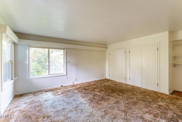 unfurnished bedroom featuring two closets and carpet