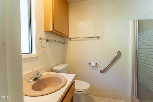 full bath featuring toilet, a shower with shower door, vanity, and baseboards