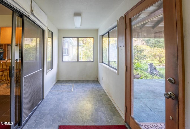 unfurnished sunroom featuring stone flooring and baseboards