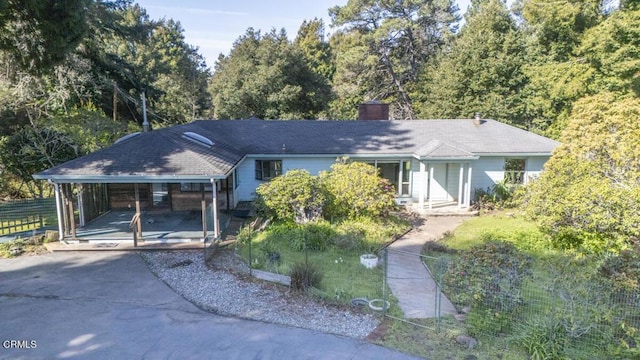 ranch-style home with driveway, fence, a chimney, and an attached carport