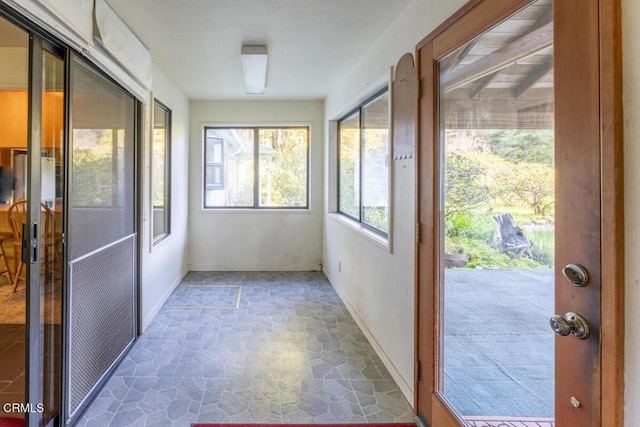 unfurnished sunroom with stone finish floor and baseboards