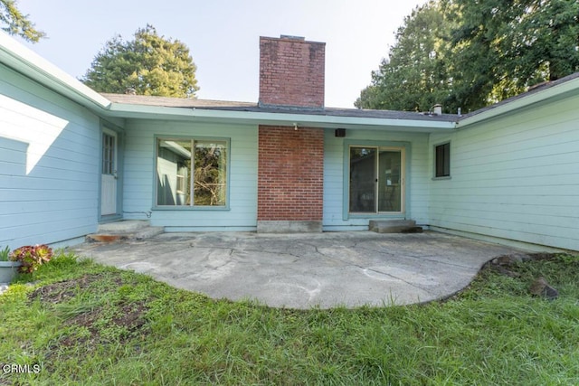back of property featuring a chimney and a patio area