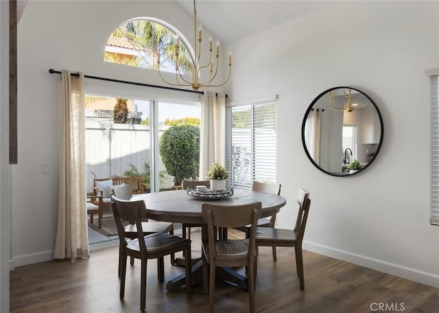 dining area featuring dark wood finished floors, a notable chandelier, high vaulted ceiling, and baseboards