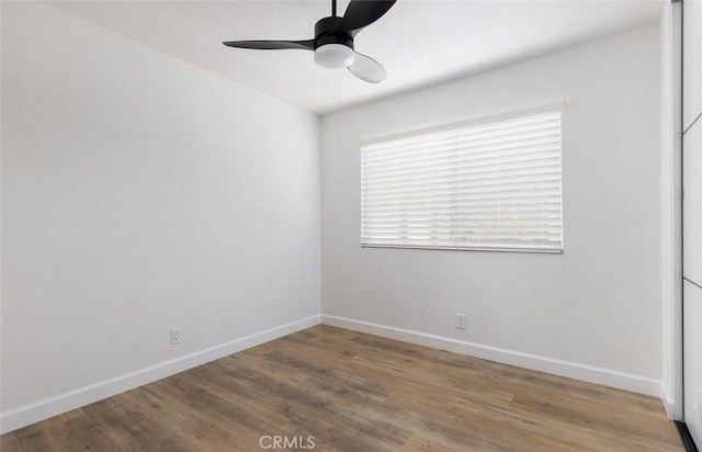 empty room featuring baseboards, wood finished floors, and a ceiling fan