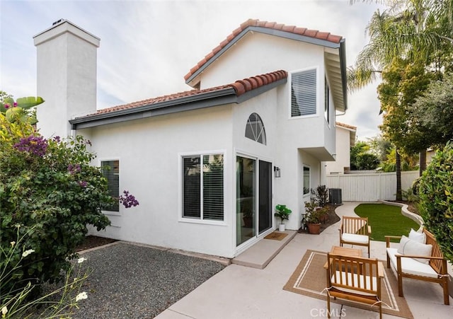 rear view of property with an outdoor living space, fence, a tile roof, stucco siding, and a patio area