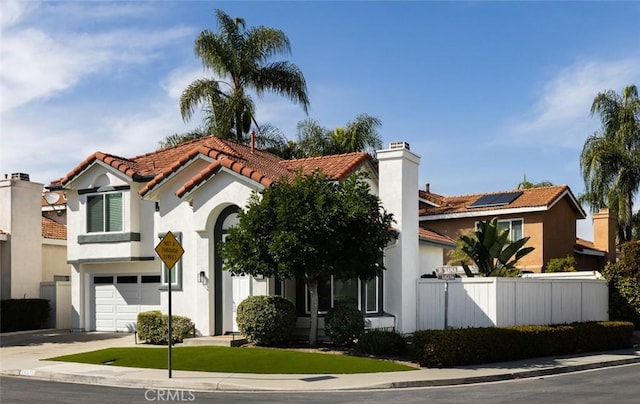 view of front of property with fence, a tile roof, concrete driveway, stucco siding, and an attached garage