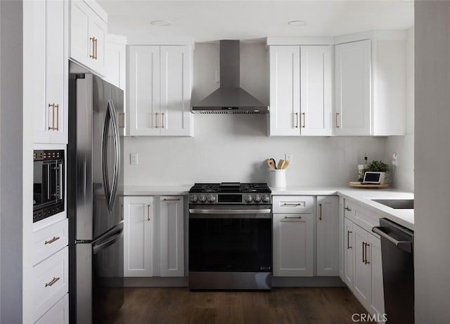 kitchen featuring dark wood finished floors, light countertops, appliances with stainless steel finishes, white cabinets, and wall chimney exhaust hood