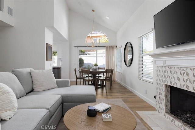 living room with high vaulted ceiling, light wood-style flooring, recessed lighting, a fireplace, and baseboards