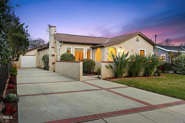 mediterranean / spanish-style house featuring stucco siding, driveway, an outdoor structure, a front yard, and a garage