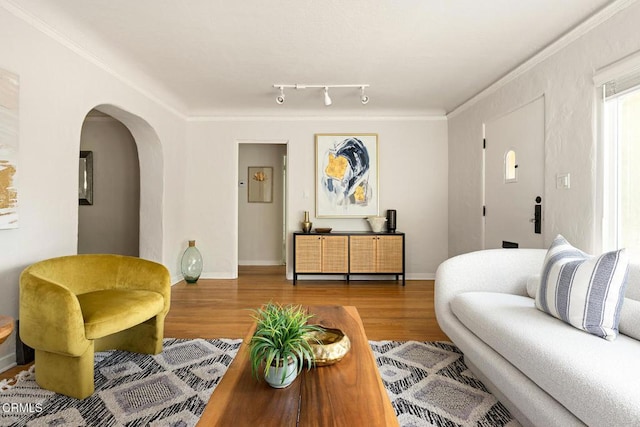 living area with baseboards, arched walkways, wood finished floors, and ornamental molding