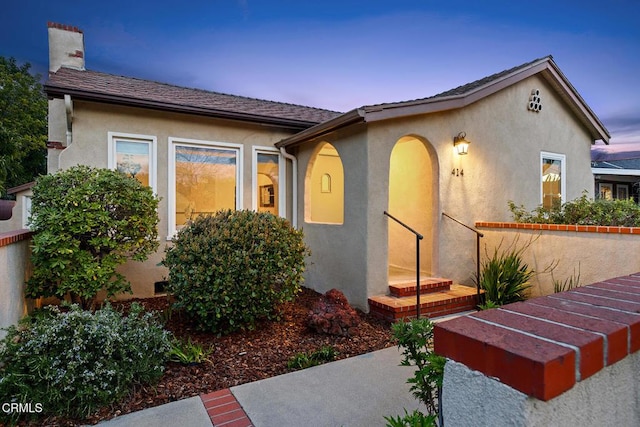 view of front of home featuring stucco siding and a chimney