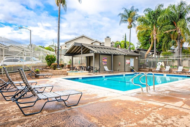 community pool with a community hot tub, a patio, and fence