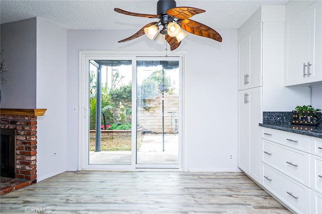 interior space featuring a wealth of natural light, light wood-type flooring, a textured ceiling, and a fireplace