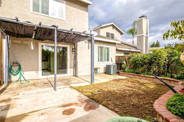 rear view of property with stucco siding, a pergola, a patio, cooling unit, and a chimney