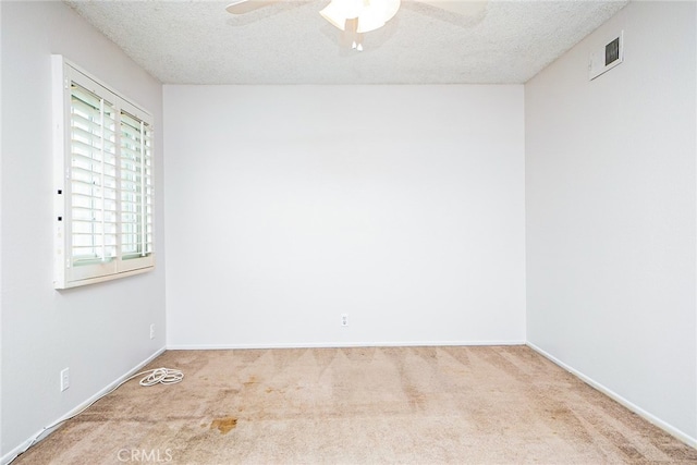 unfurnished room with visible vents, a ceiling fan, a textured ceiling, carpet floors, and baseboards