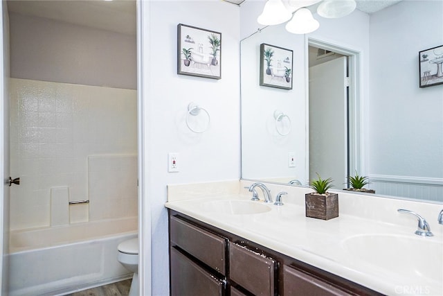 full bath with a sink, toilet, wood finished floors, and double vanity