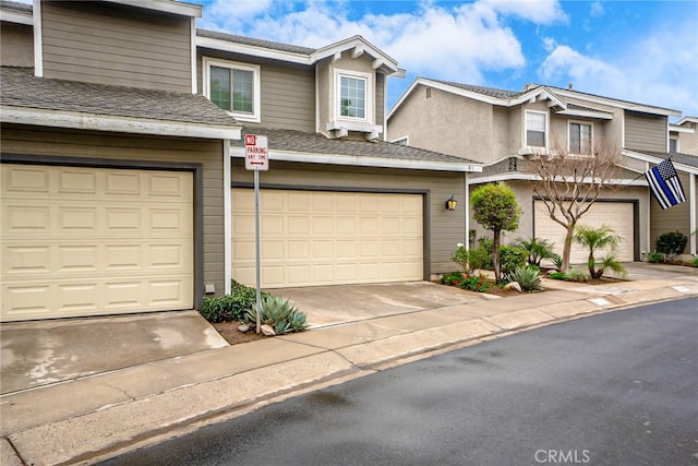 townhome / multi-family property featuring stucco siding, an attached garage, concrete driveway, and roof with shingles