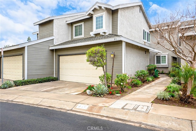 view of front of home with stucco siding, an attached garage, and driveway