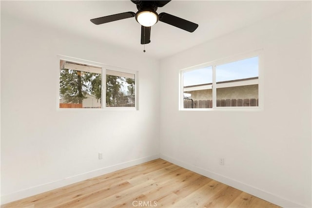 spare room with a healthy amount of sunlight, baseboards, and wood finished floors