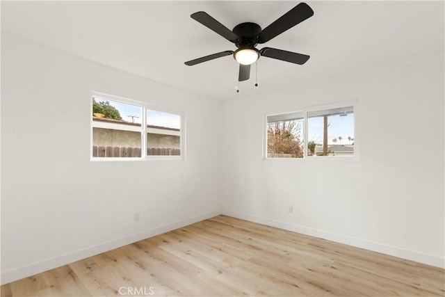 spare room with baseboards, wood finished floors, and a ceiling fan