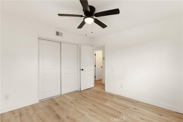 unfurnished bedroom featuring visible vents, baseboards, a closet, and wood finished floors