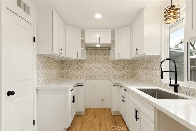 kitchen featuring a sink, visible vents, tasteful backsplash, and under cabinet range hood