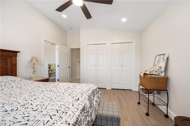 bedroom featuring baseboards, lofted ceiling, light wood-style flooring, recessed lighting, and multiple closets