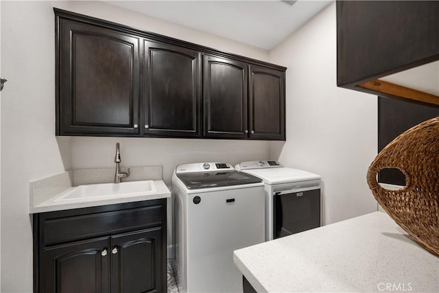 washroom featuring separate washer and dryer, cabinet space, and a sink