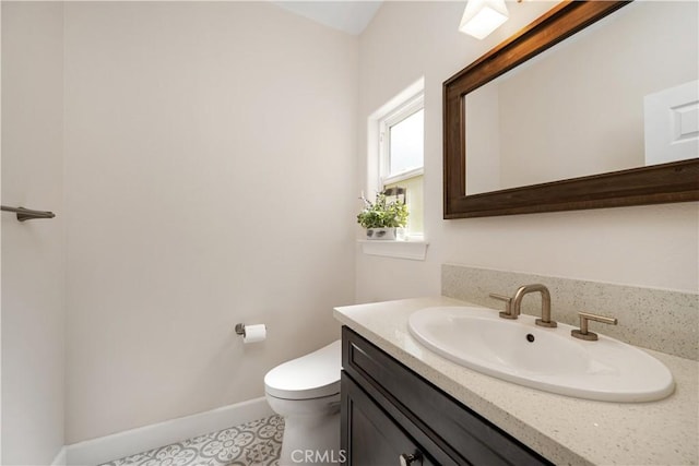 half bath with baseboards, toilet, and vanity