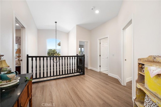 hallway with baseboards, lofted ceiling, and wood finished floors