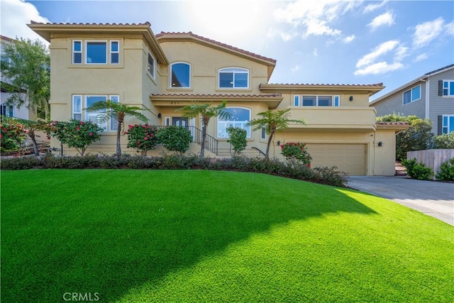 mediterranean / spanish-style home with stucco siding, driveway, an attached garage, and a front lawn