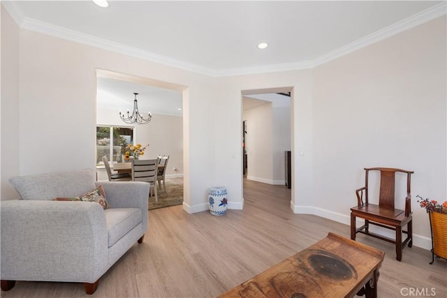 living room with light wood finished floors, an inviting chandelier, crown molding, and baseboards