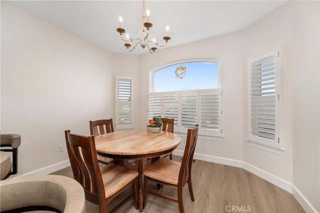 dining area with an inviting chandelier, light wood-style floors, and baseboards