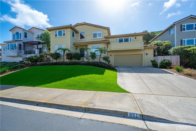 mediterranean / spanish-style house featuring stucco siding, a front lawn, driveway, an attached garage, and a tiled roof